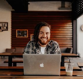 man sitting at mac laptop smiling